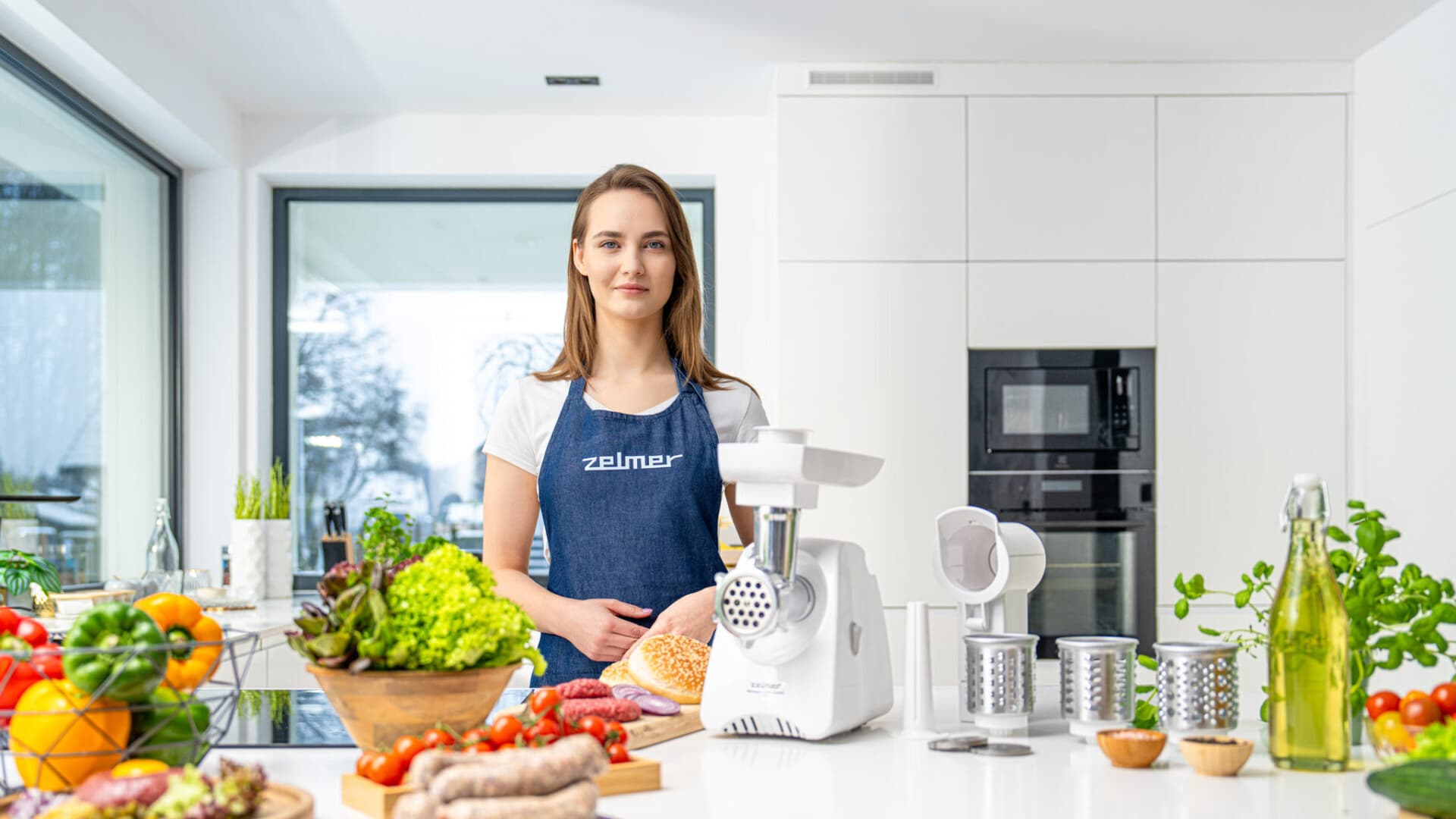 Sesja produktowa lifestyle AGD Zelmer w nowoczesnej kuchni, modelka przy maszynce do mielenia z akcesoriami i składnikami