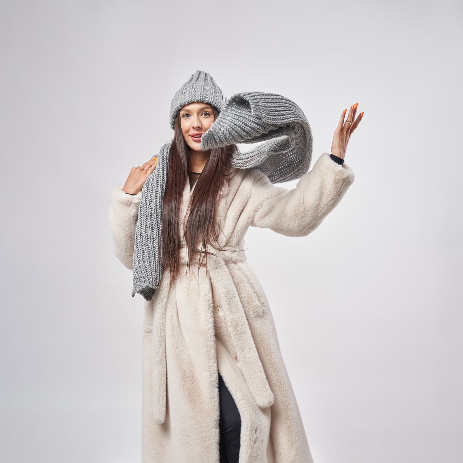 Profesjonalna fotografia mody w Warszawie - modelka w zimowym płaszczu i czapce podczas dynamicznej sesji lookbook w studio Packshothouse.