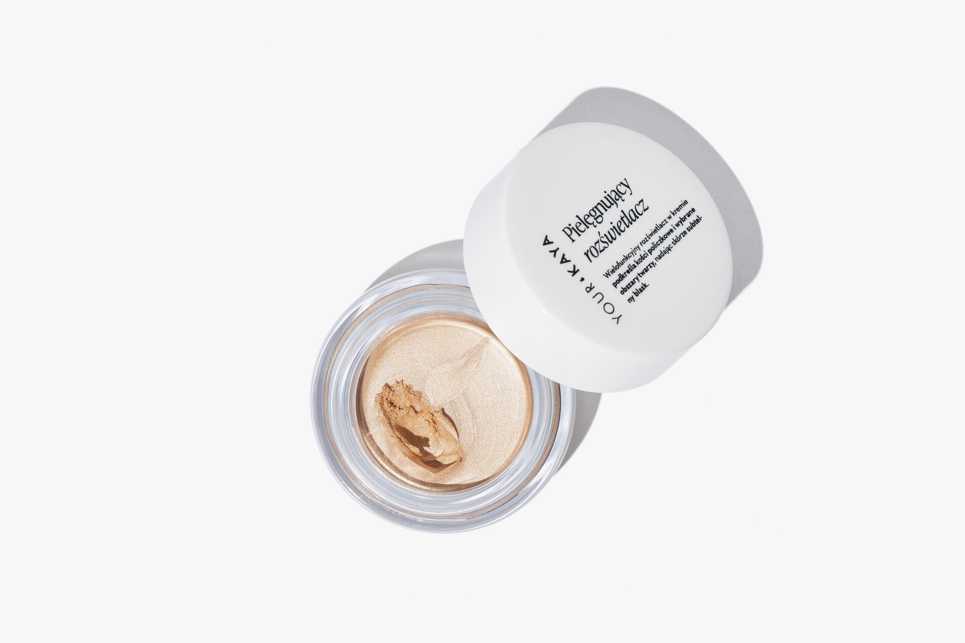 Profesjonalna fotografia produktowa: otwarty słoiczek z kremowym rozświetlaczem Your Kaya, minimalistyczne zdjęcie typu flat lay na białym tle z ostrym cieniem.