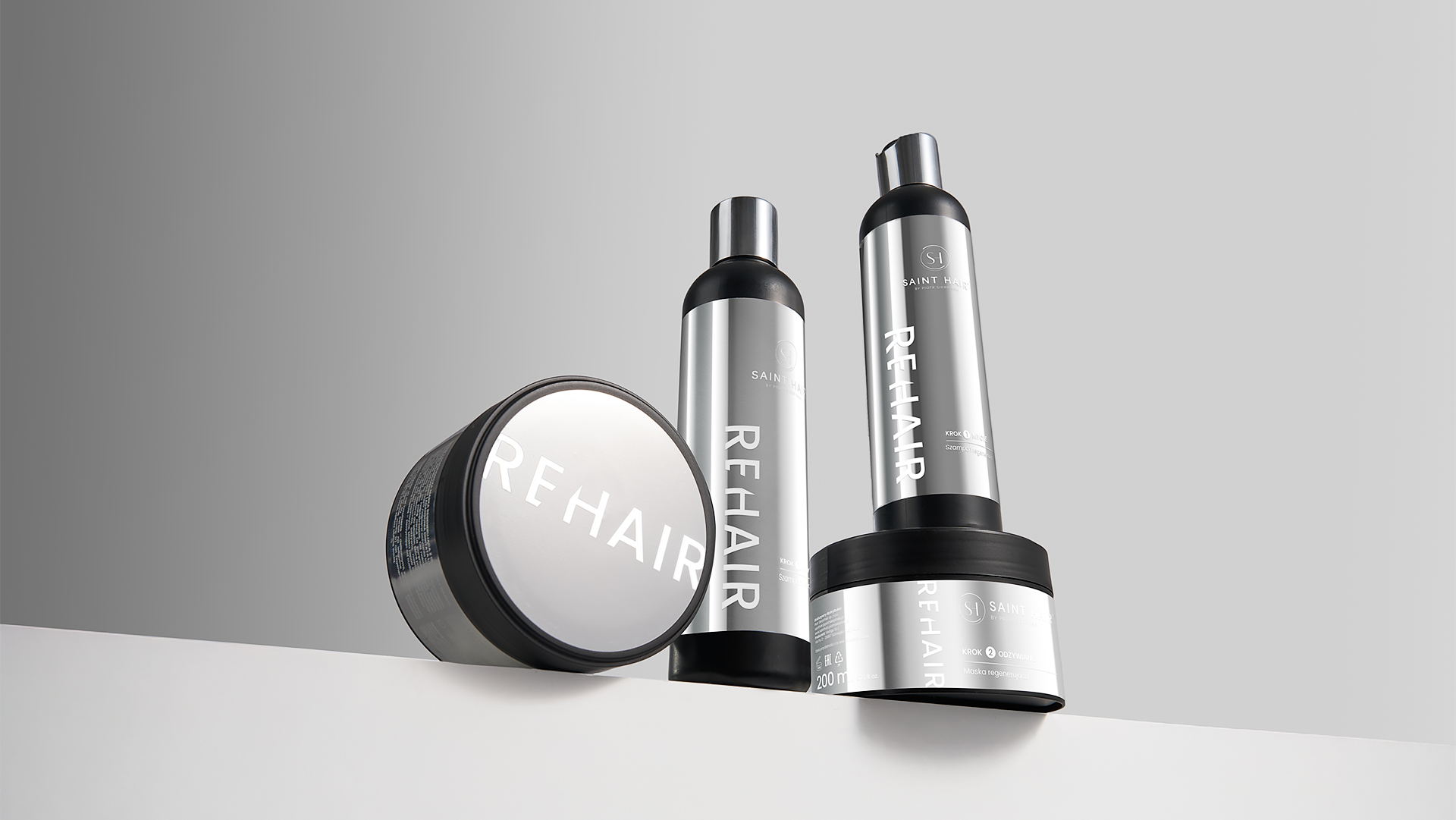 Kosmetyki do włosów REHAIR Saint Hair, packshot produktowy na szarym tle, butelki i słoiki w aranżacji