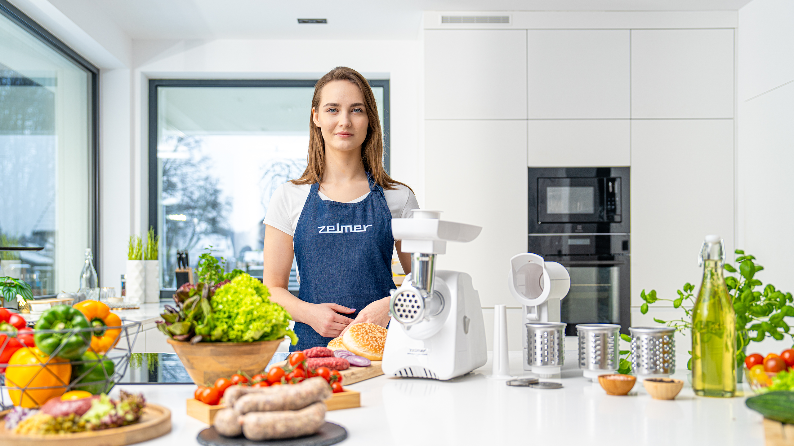 Sesja produktowa lifestyle AGD Zelmer w nowoczesnej kuchni, modelka przy maszynce do mielenia z akcesoriami i składnikami